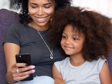 Mom with her daughter reading from an cell phone.