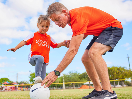 Soccer Shots coach helping a young child in a Soccer Shots jersey